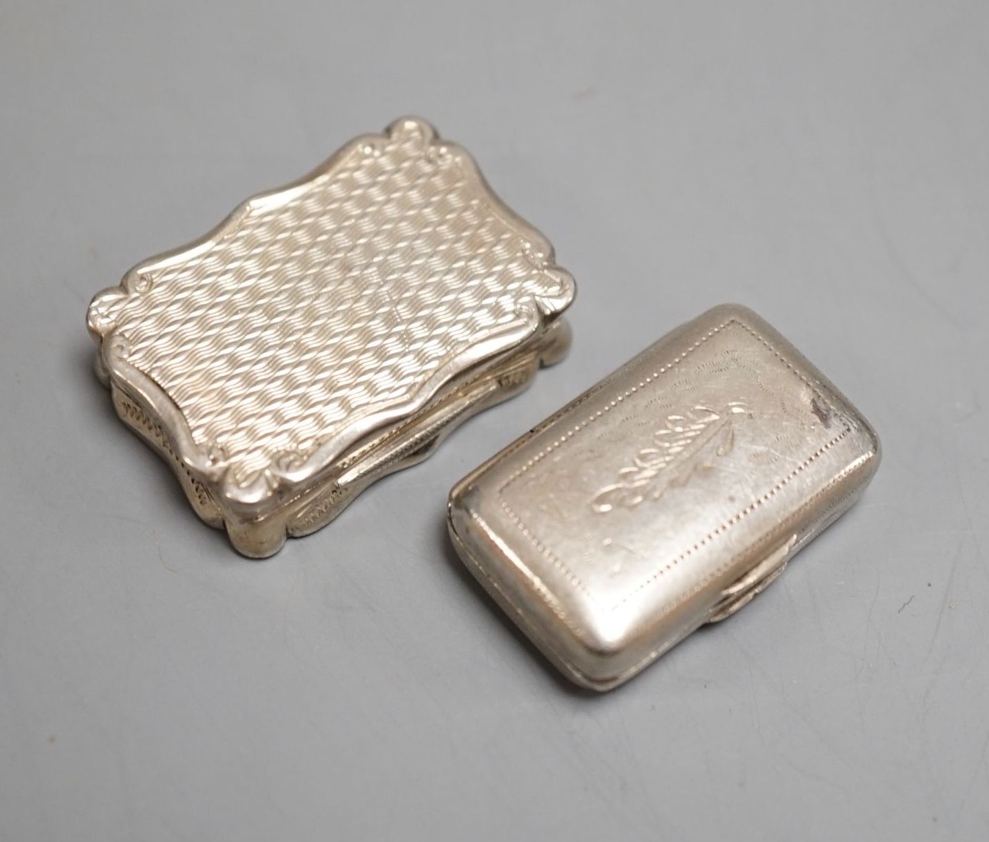 A George III engraved silver rectangular vinaigrette, by Wardell & Kempson, Birmingham, 1811, 27mm and a later silver vinaigrette by Frederick Marsen, Birmingham, 1868, 30mm.